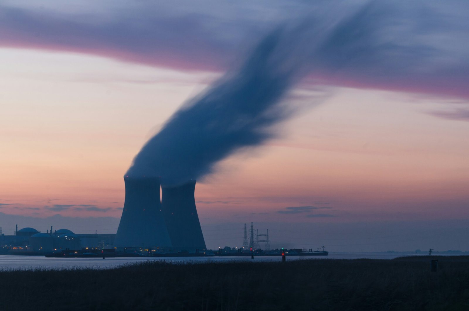 israelagent.com skyline photography of nuclear plant cooling tower blowing smokes under white and orange sky at daytime