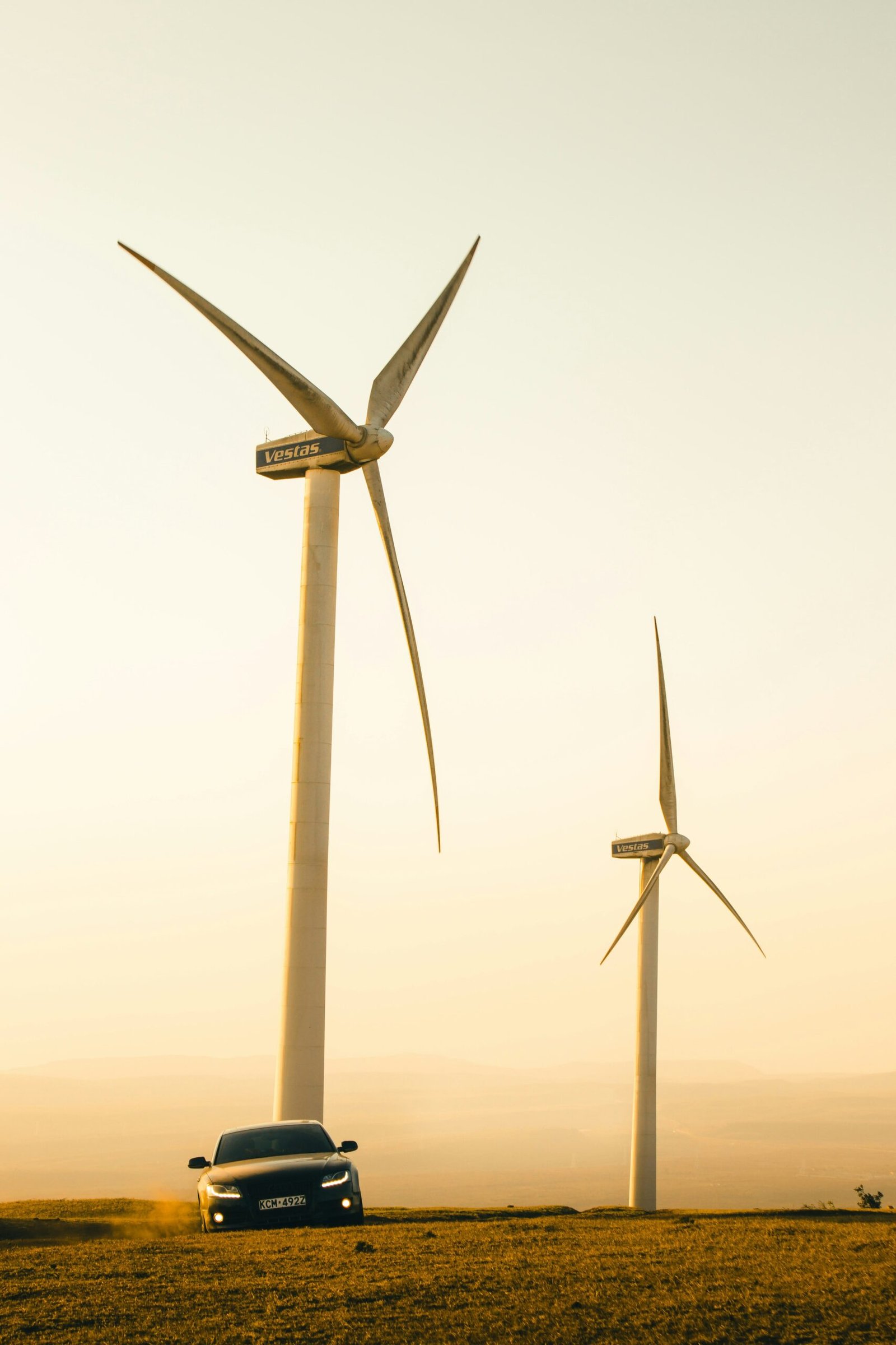 A car driving past wind turbines in a field