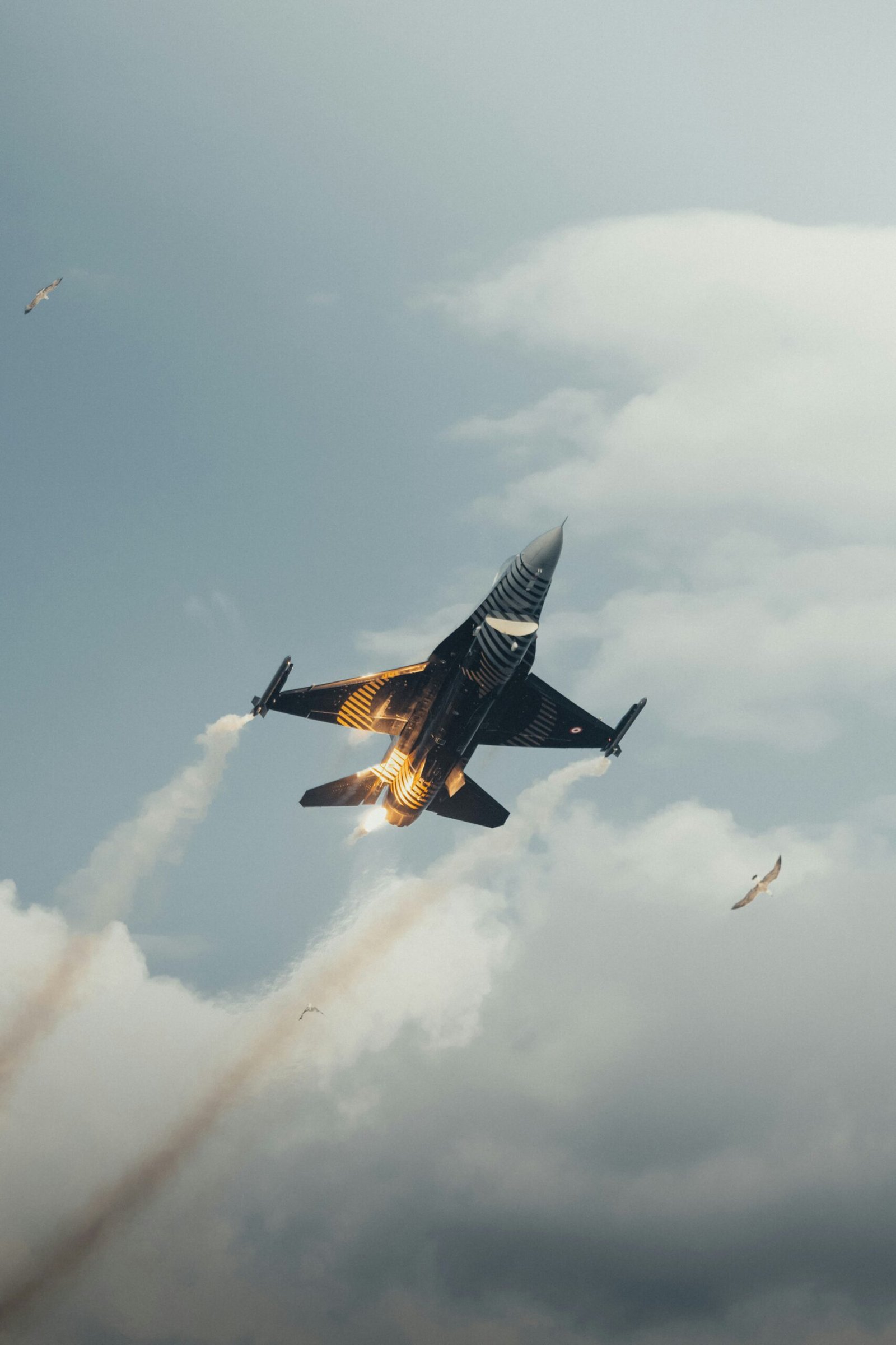 A fighter jet flying through a cloudy blue sky